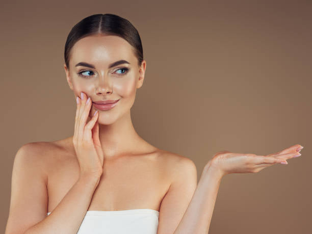 woman with radiant skin gently touching her cheek, emphasizing the nourishing effects of DermaSkin’s premium skincare products