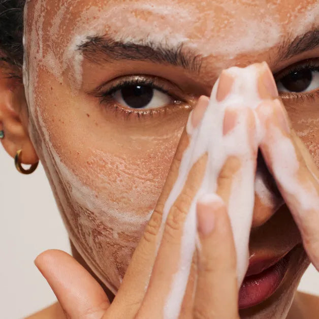 Close-Up of a woman cleansing her face with a foaming cleanser, representing the deep cleaning power of DermaSkin’s Smooth Sailing Citrus Cleanser.